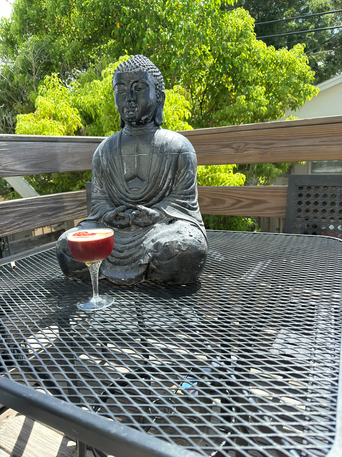 A cocktail beside the Buddha statue on the sunny back patio