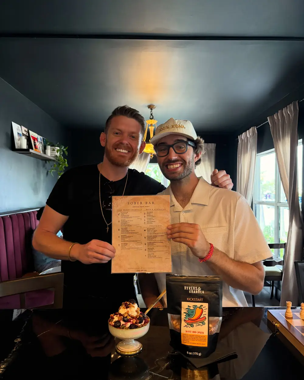 Sober Bar’s owners holding the opening menu at the bar