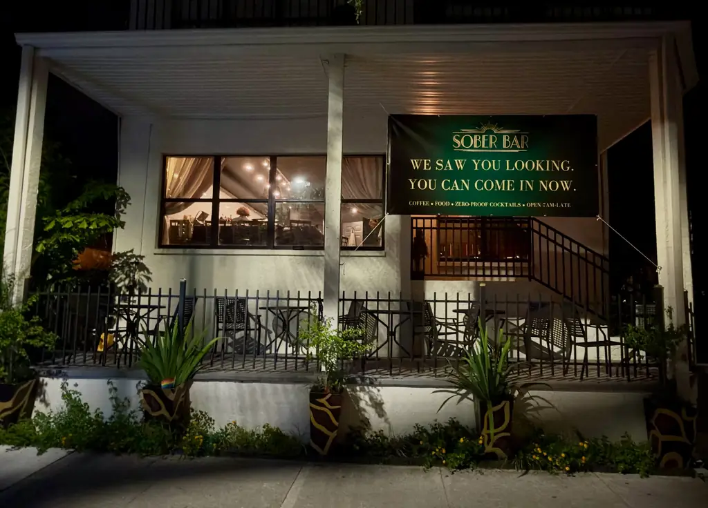 The porch on Beach Boulevard at night, lit up under the banner: We saw you looking. You can come in now.